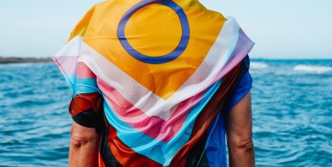 Person wearing pride progress flag on shoulders