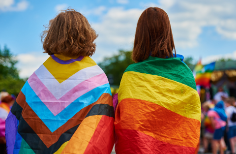 Two people wrapped in rainbow pride flags