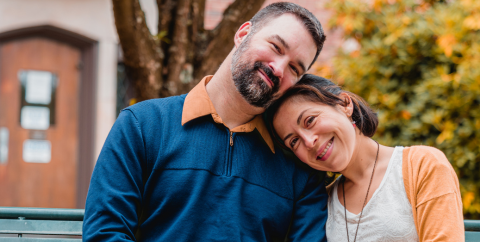 a man and a woman leaning their heads together and smiling