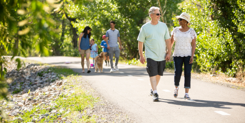 a couple walking on a path with another family behind them