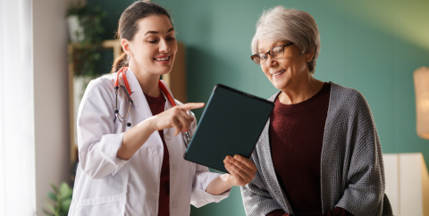 a female physician points to an ipad to educate an older woman