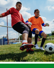 Two teenagers playing soccer outside